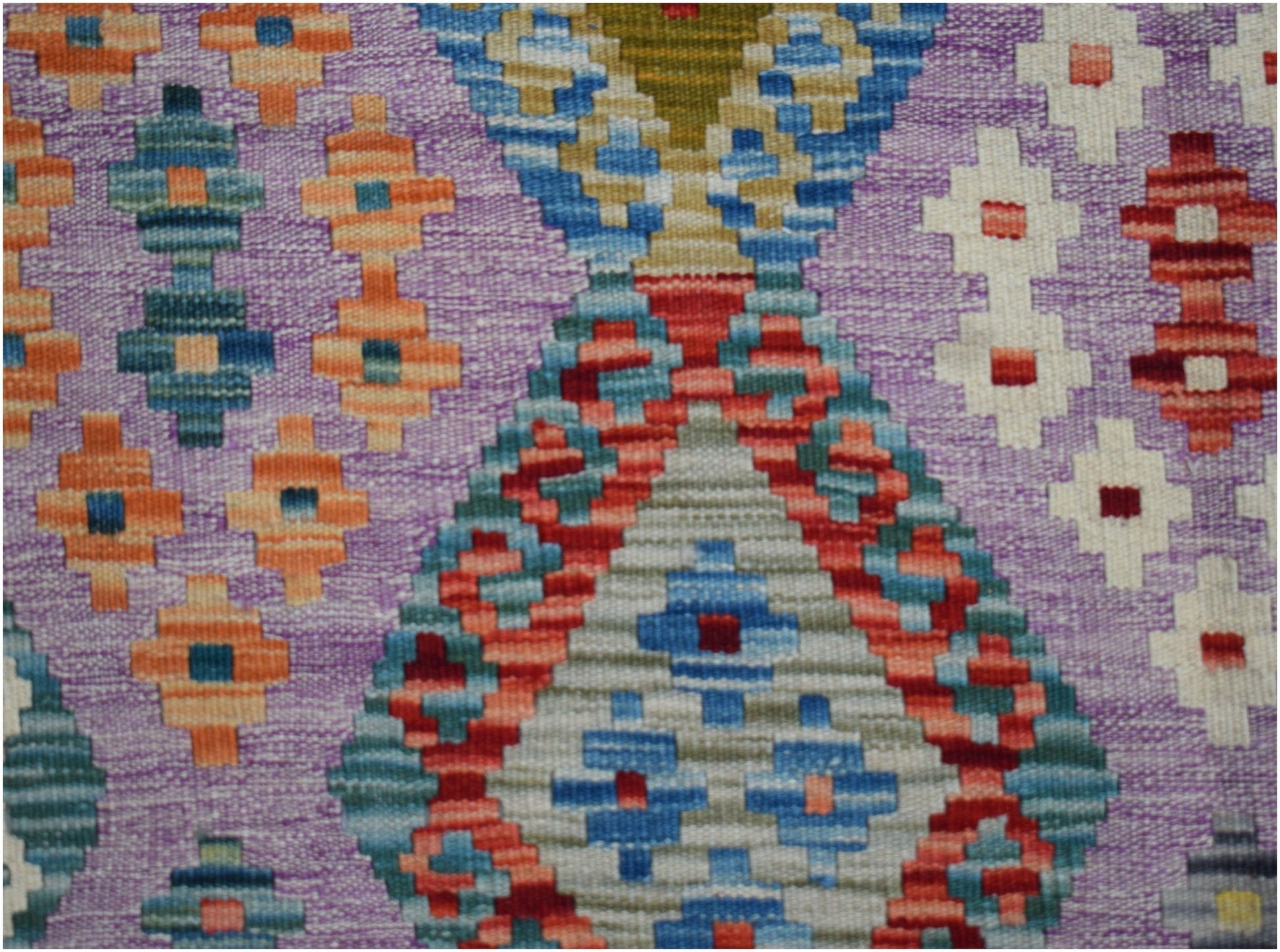 Handwoven Afghan Maimana kilim featuring a geometric pattern in vibrant colors on a purple base.