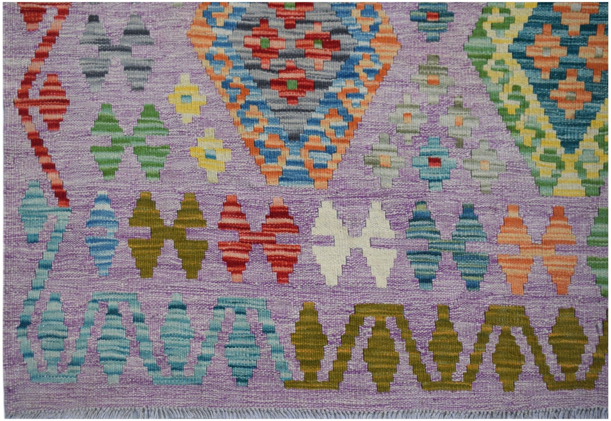 Handwoven Afghan Maimana kilim rug featuring a vibrant geometric pattern on a purple background.