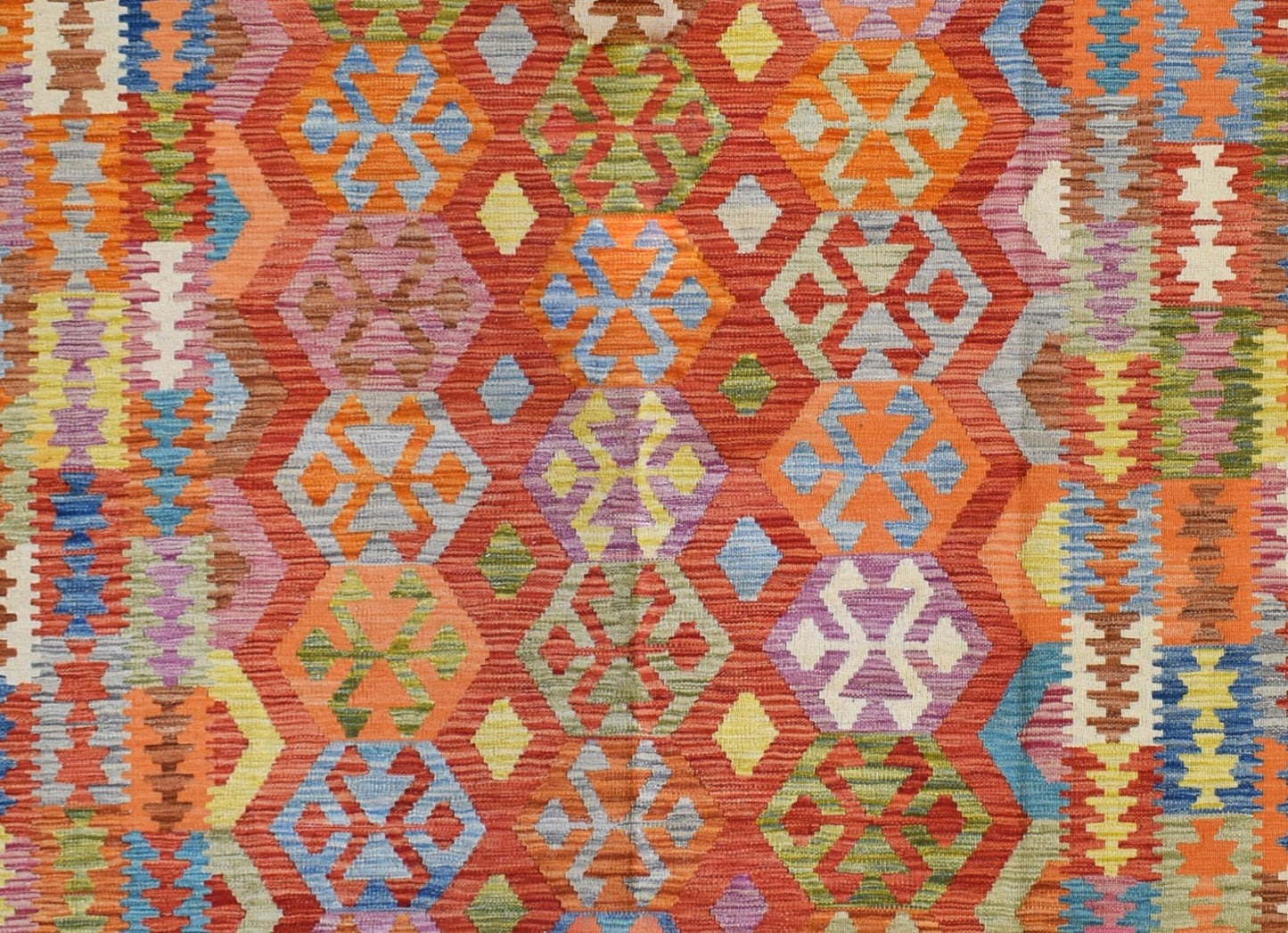 Handmade Afghan Maimana kilim rug featuring a vibrant geometric pattern in rich, multicolored wool.