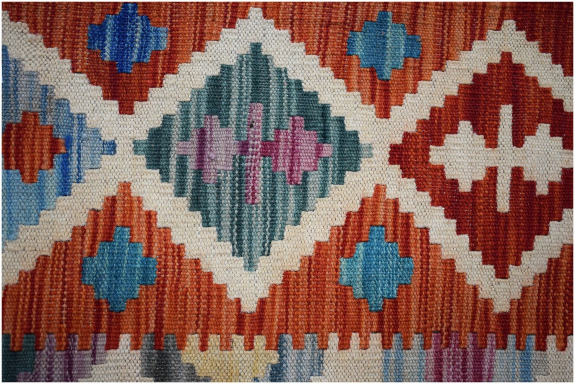 Handwoven Afghan Maimana Kilim featuring a geometric pattern in vibrant orange, blue, and cream.