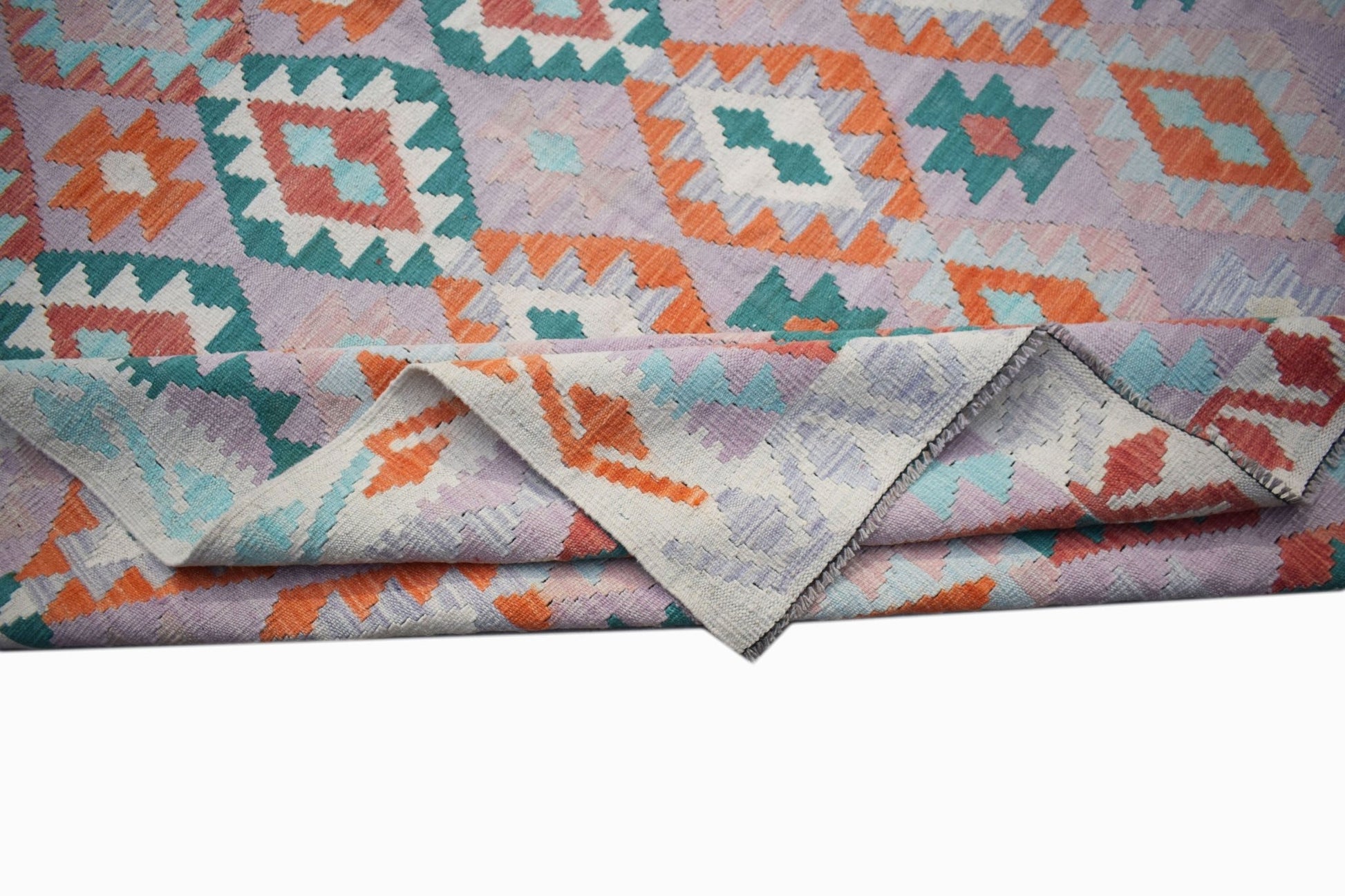 A handmade Afghan Maimana kilim rug featuring a geometric pattern in orange, teal, and lavender.