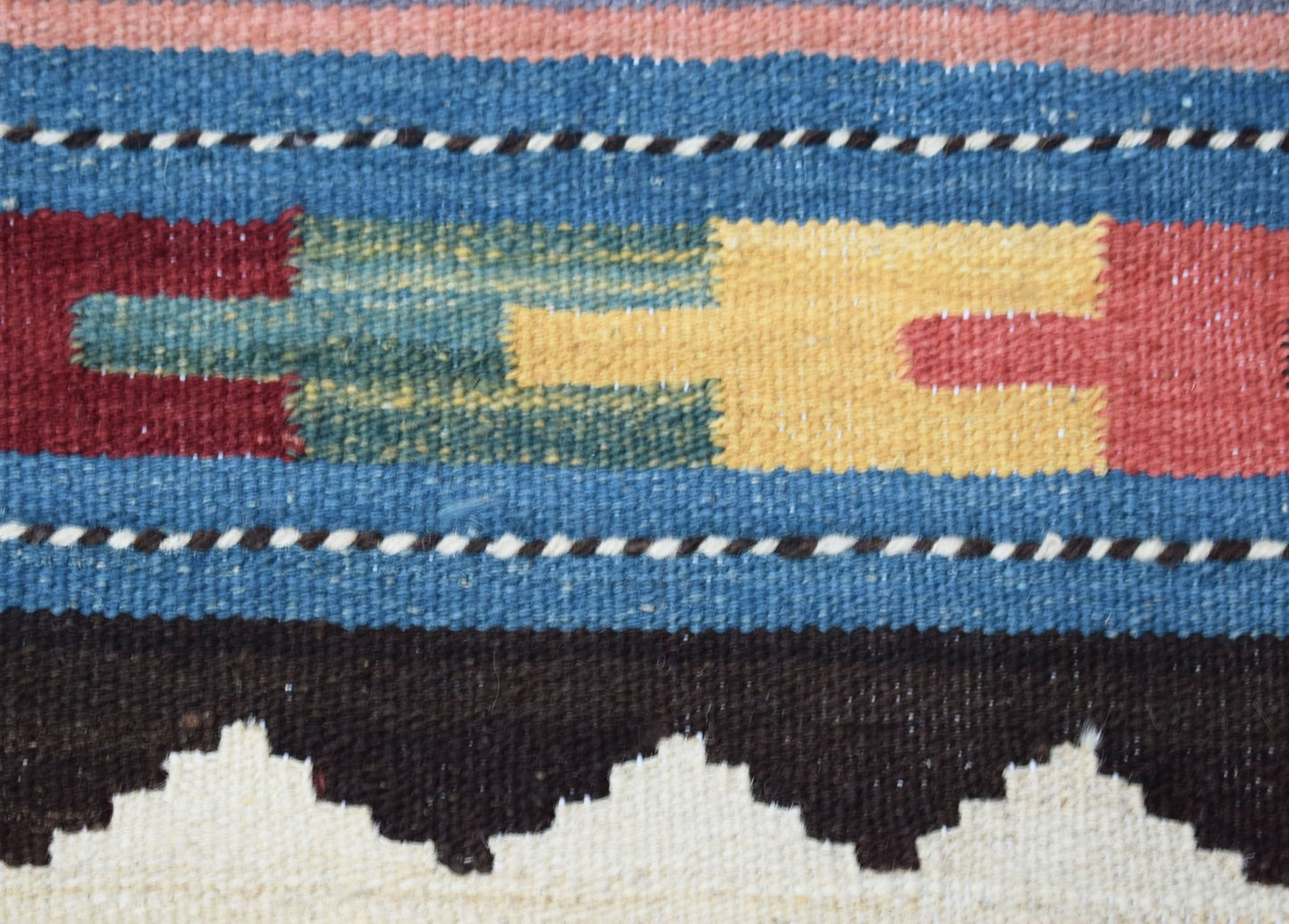 A close-up of a handmade Afghan Maimana kilim featuring geometric patterns in wool.