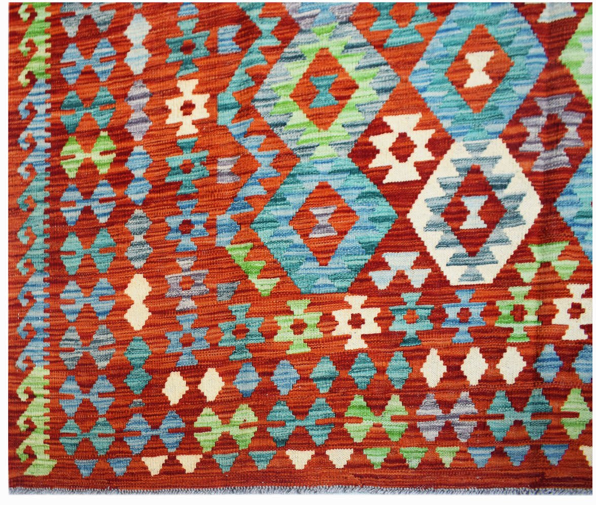 Handwoven Afghan Maimana kilim rug featuring a geometric pattern in shades of orange, blue, and green.
