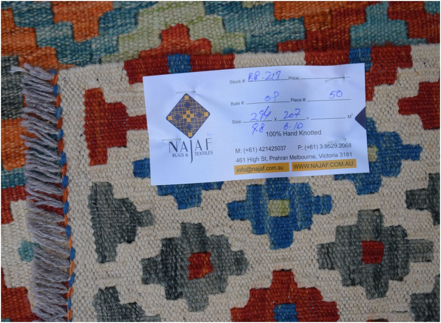 An Afghan Maimana Kilim rug featuring a geometric pattern in red, blue, and green on a cream base.