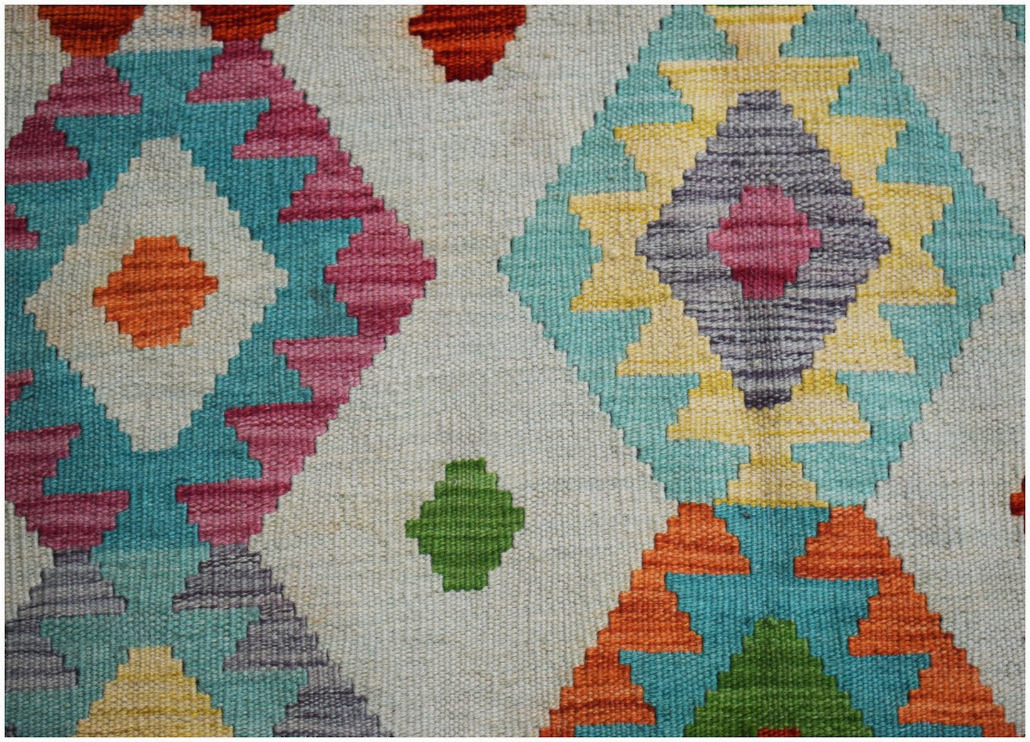 Handwoven Afghan Maimana kilim rug featuring a colorful geometric diamond pattern on a cream base.