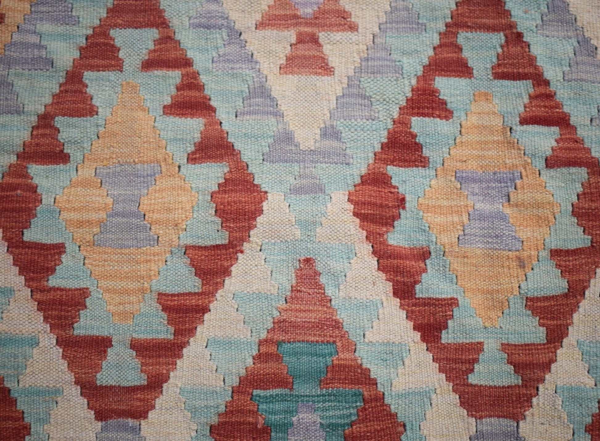 Handwoven Afghan Maimana kilim featuring a geometric diamond pattern in red, blue, and tan wool.