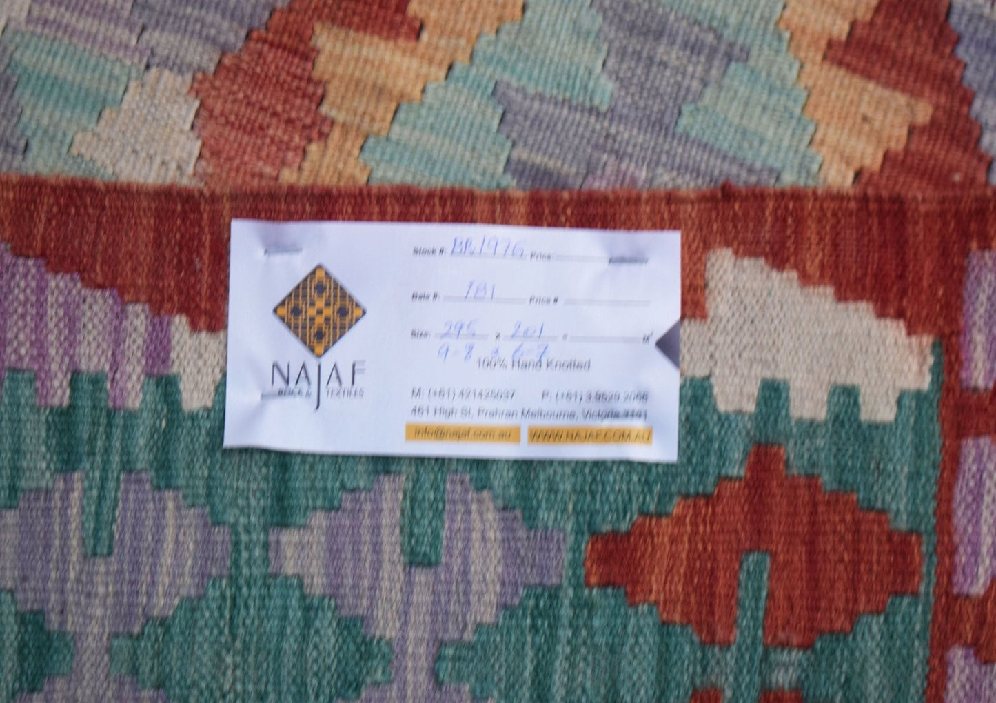 A handmade Afghan Maimana kilim featuring a geometric pattern in red, green, and purple tones.