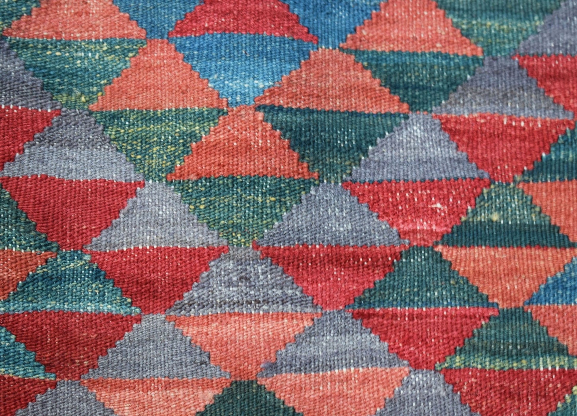Handwoven Afghan Maimana kilim featuring a repeating geometric pattern of multicolored triangles.