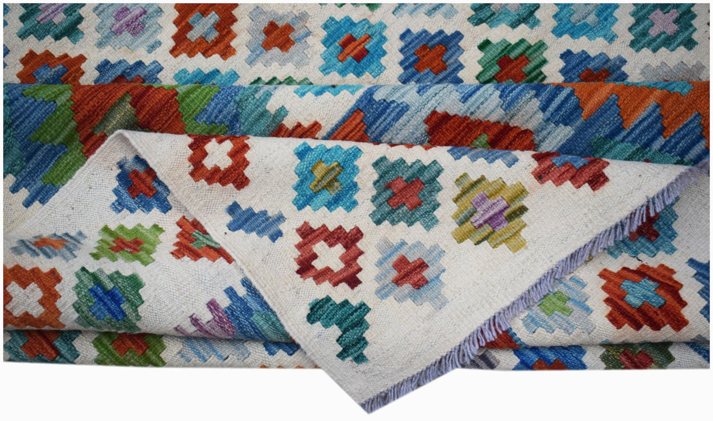 Handwoven Afghan Maimana kilim rug featuring a colorful geometric pattern on a cream background.