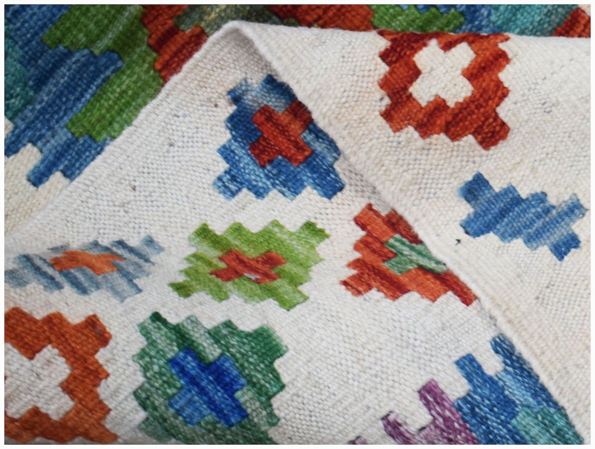 A handmade Afghan Maimana kilim featuring a geometric pattern in vibrant red, blue, and green.