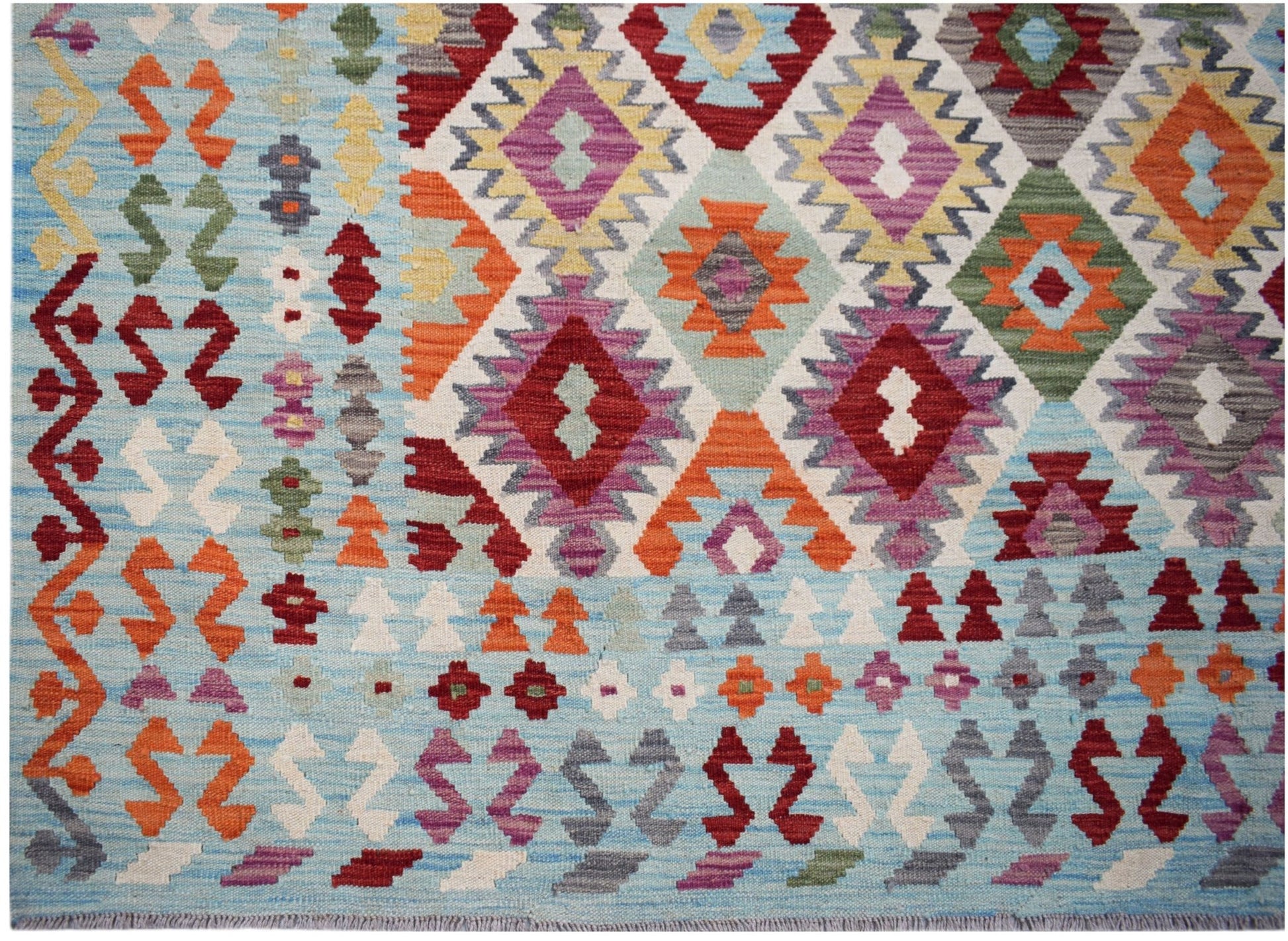 Handwoven Afghan Maimana kilim featuring a light blue background with colorful geometric patterns.