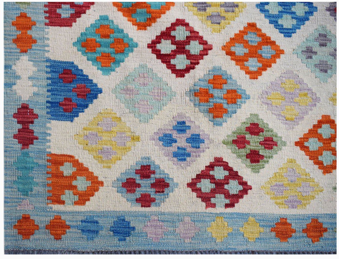 Handwoven Afghan Maimana kilim featuring a colorful geometric diamond pattern on a cream background.