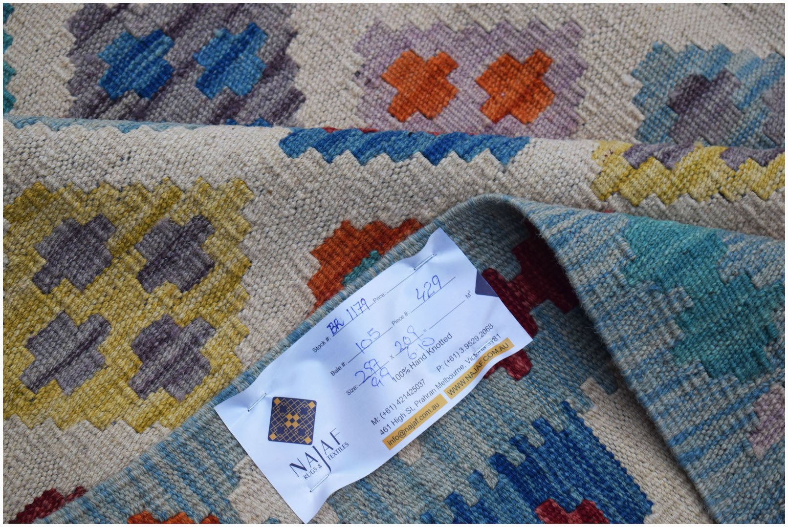 A handwoven Afghan Maimana kilim featuring a geometric pattern in vibrant, multicolored wool.