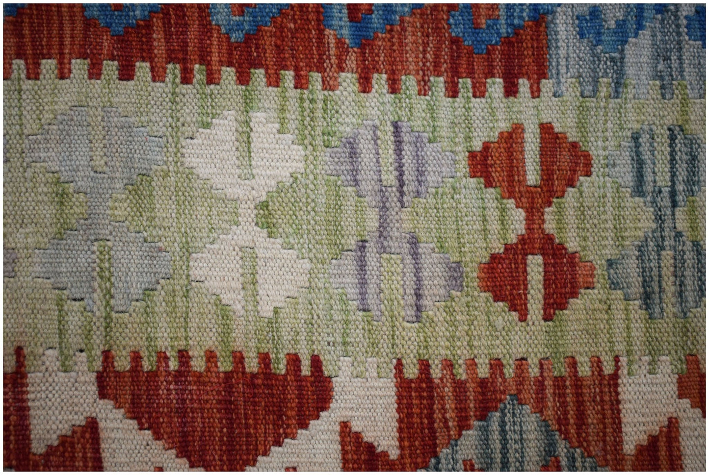 A close-up of a handmade Afghan Maimana kilim featuring geometric patterns in vibrant colors.