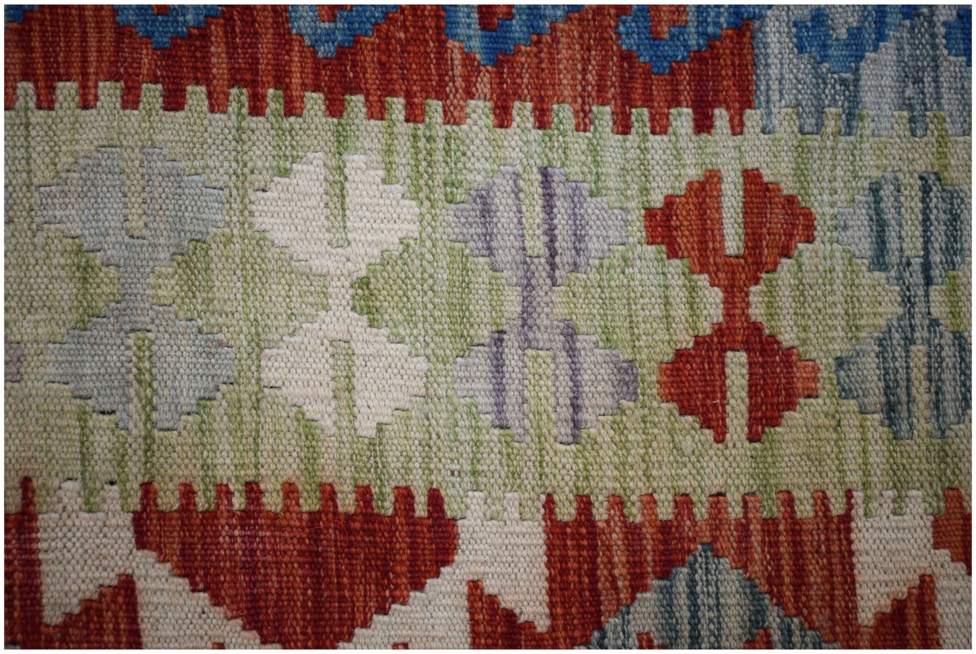 A close-up of a handmade Afghan Maimana kilim featuring geometric patterns in vibrant colors.