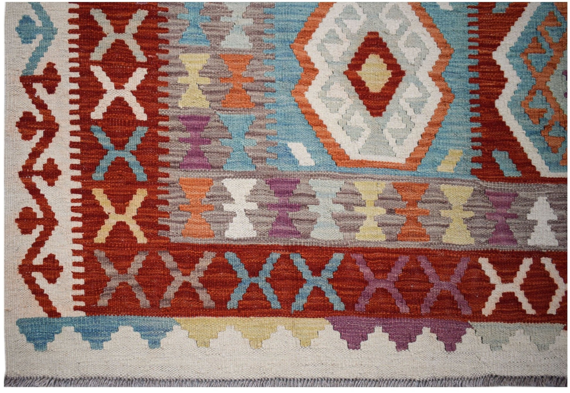 Handwoven Afghan Maimana kilim rug featuring a geometric pattern in vibrant, multi-colored wool.