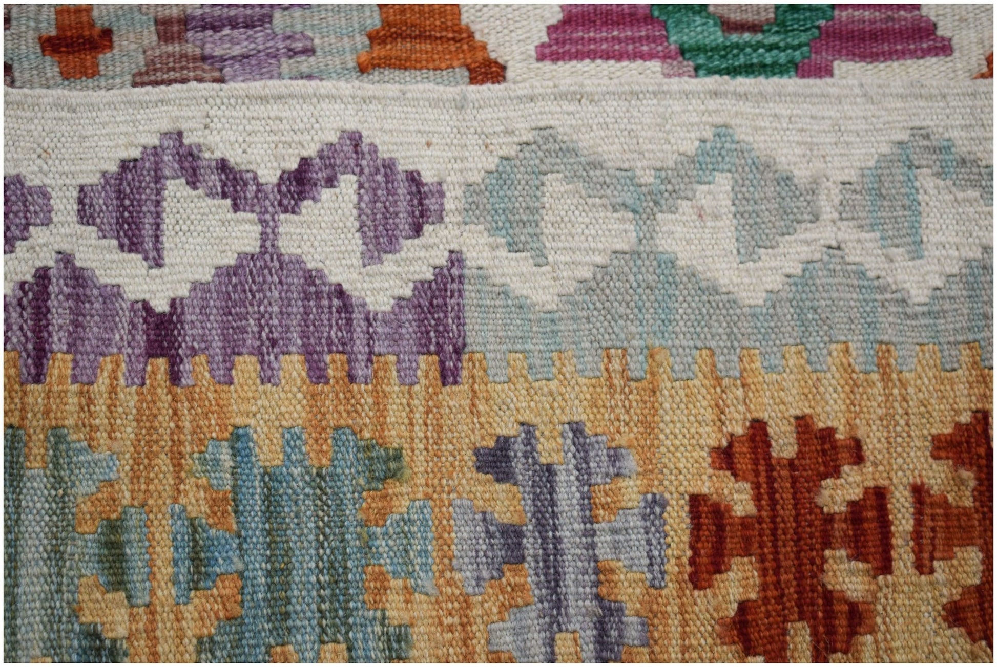 A handmade Afghan Maimana kilim featuring geometric patterns in purple, orange, and blue wool.