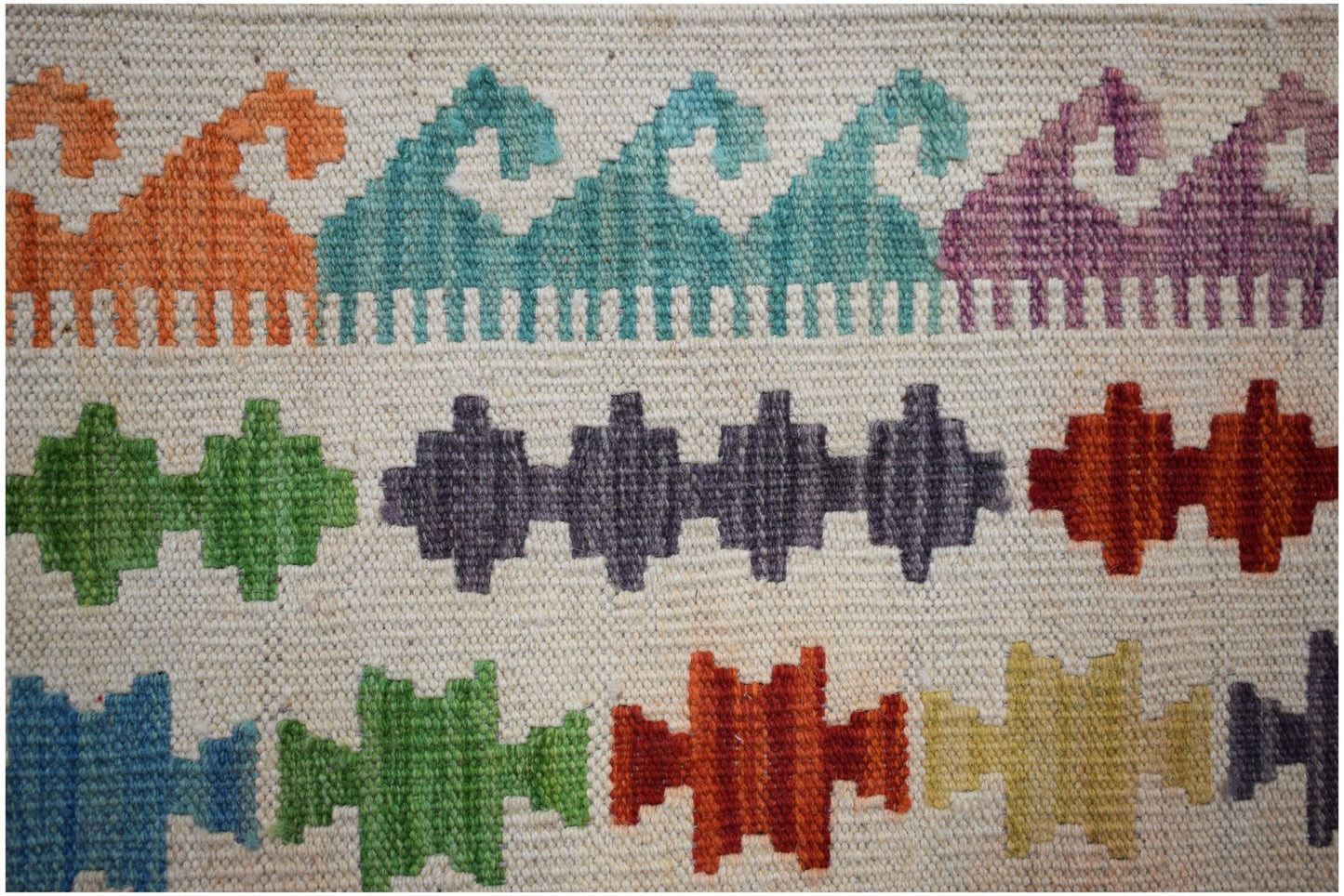 Handwoven Afghan Maimana kilim featuring colorful geometric patterns on a cream wool background.