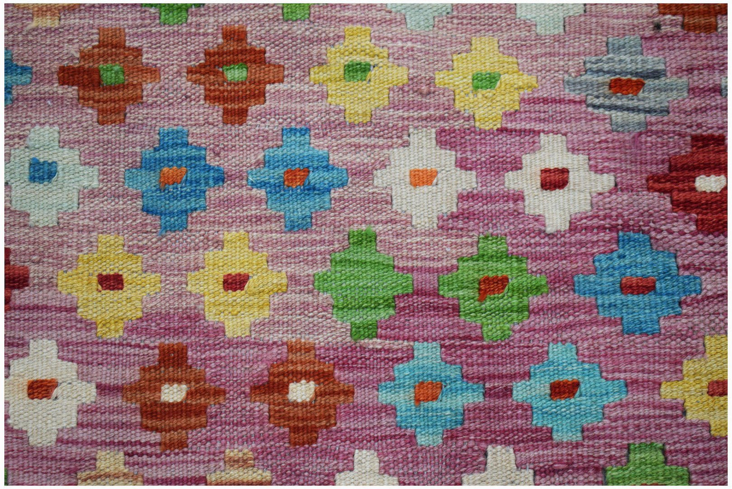 A handmade Afghan Maimana kilim featuring a repeating geometric pattern in vibrant colors.