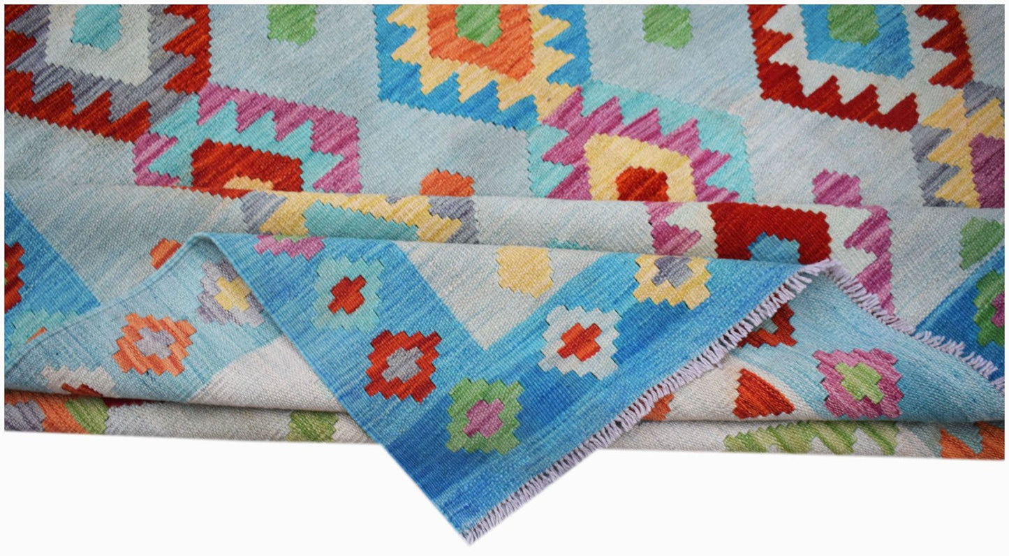 Handwoven Afghan Maimana kilim rug featuring a colorful geometric pattern on a light blue background.