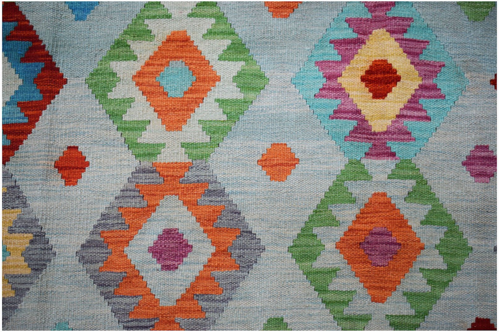 Handwoven Afghan Maimana kilim rug featuring a colorful geometric diamond pattern on a blue base.