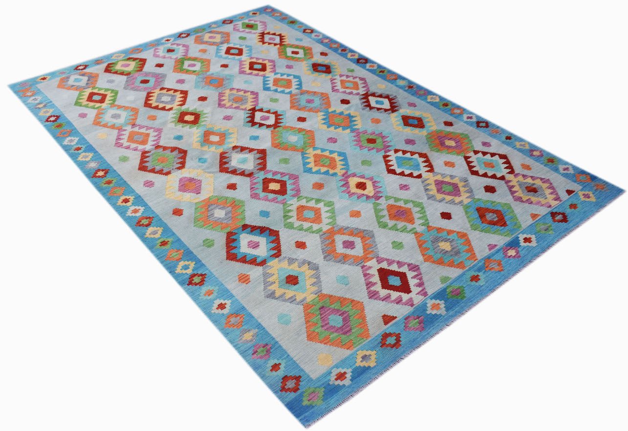 A handmade Afghan Maimana kilim rug featuring a light blue background with colorful geometric motifs.
