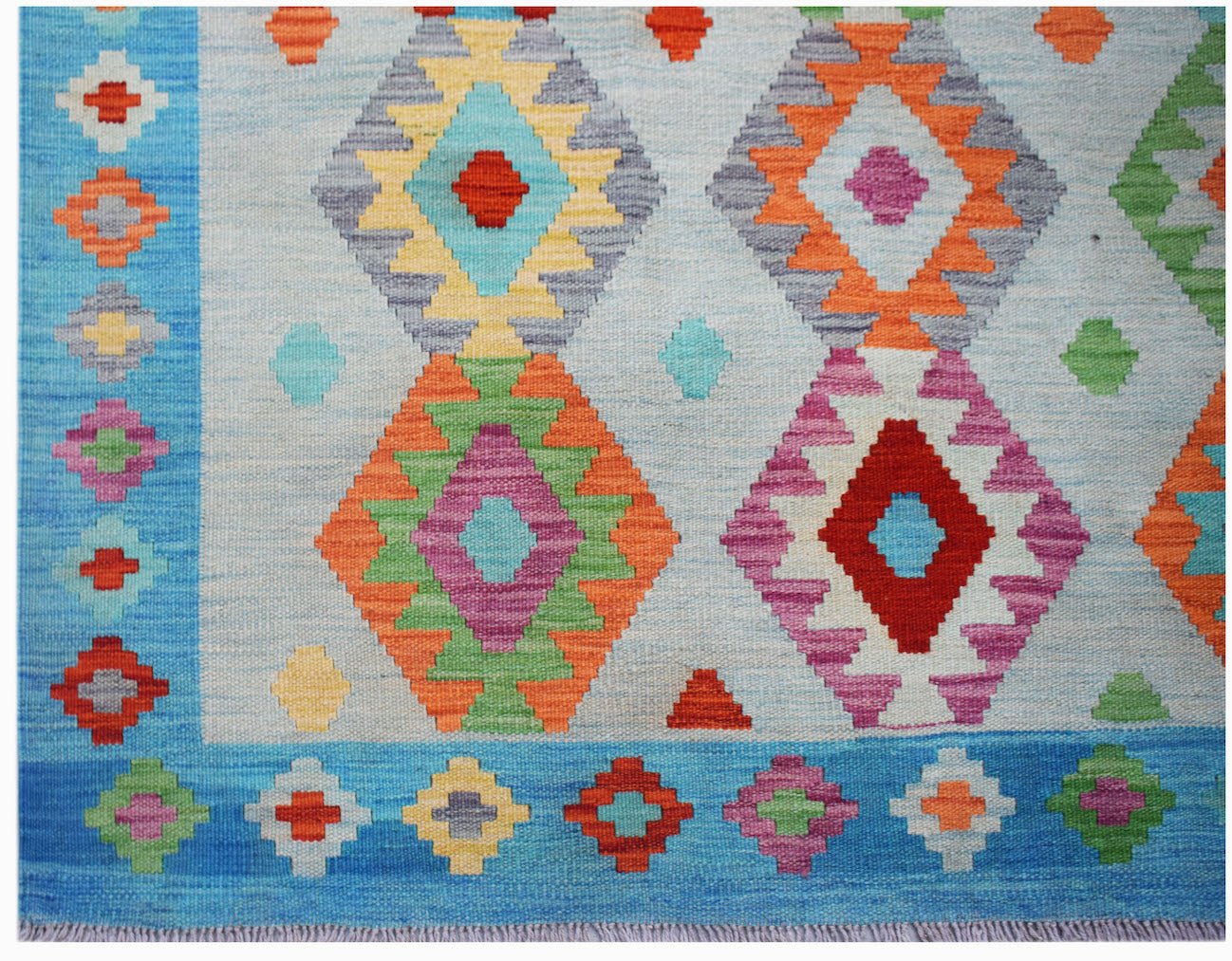 Handwoven Afghan Maimana kilim rug featuring a light blue background with colorful geometric shapes.