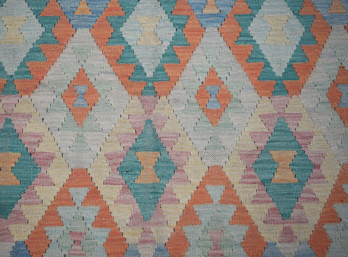 Handwoven Afghan Maimana kilim rug featuring a repeating geometric diamond pattern in soft colors.