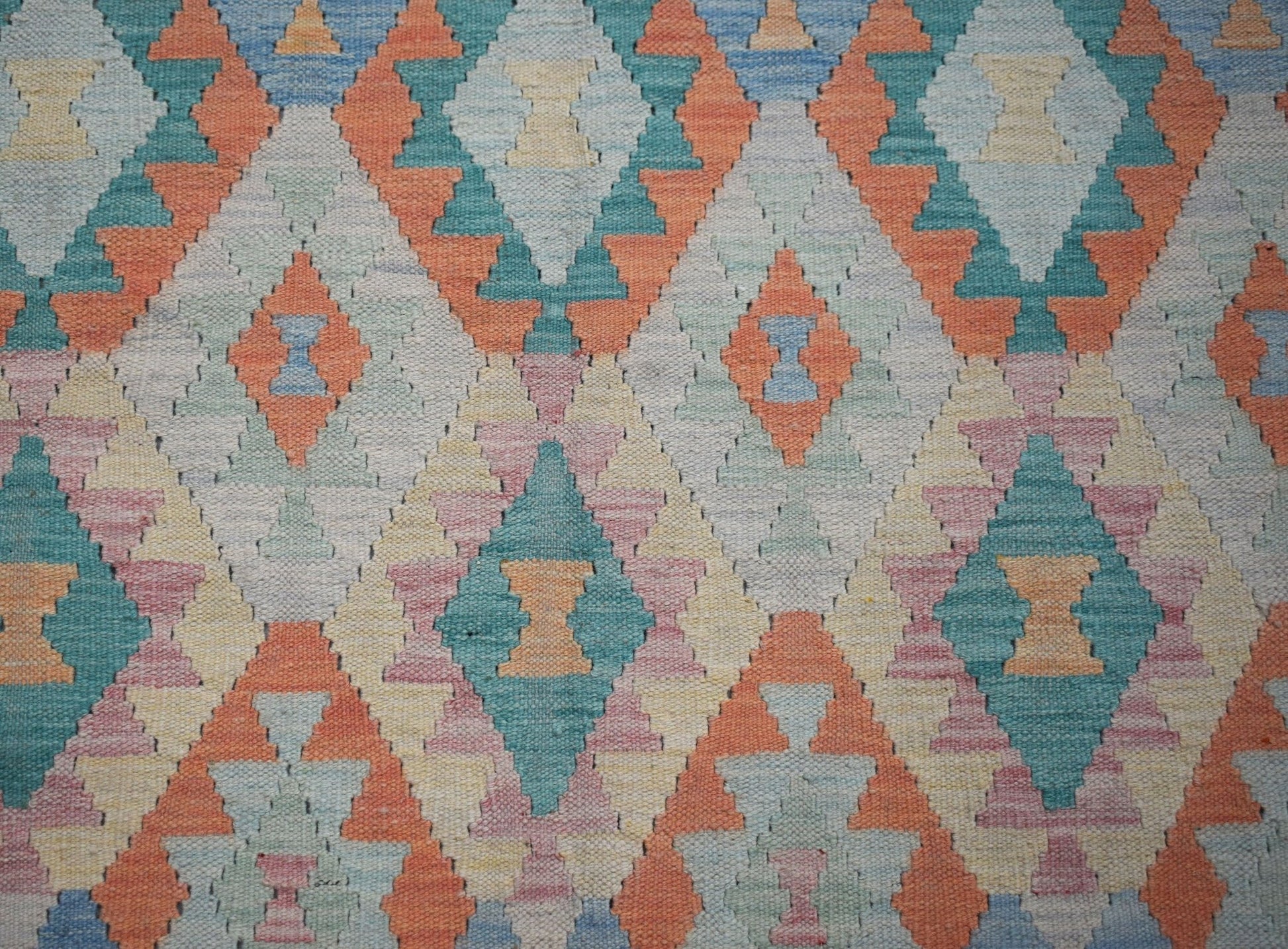 Handwoven Afghan Maimana kilim rug featuring a repeating geometric diamond pattern in soft colors.
