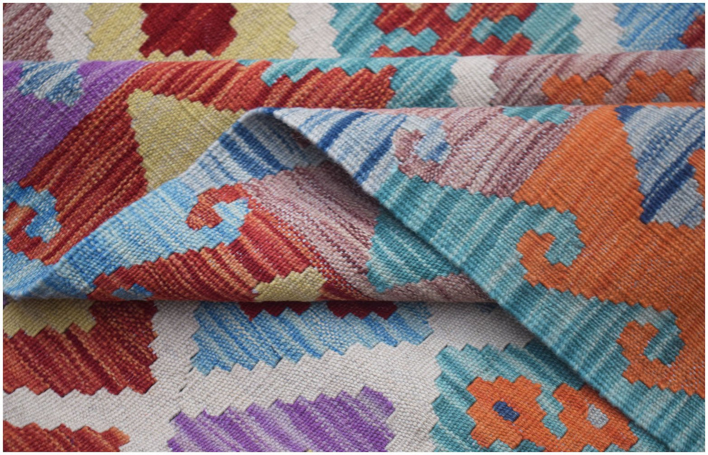 A handwoven Afghan Maimana kilim rug featuring a vibrant geometric pattern in wool.