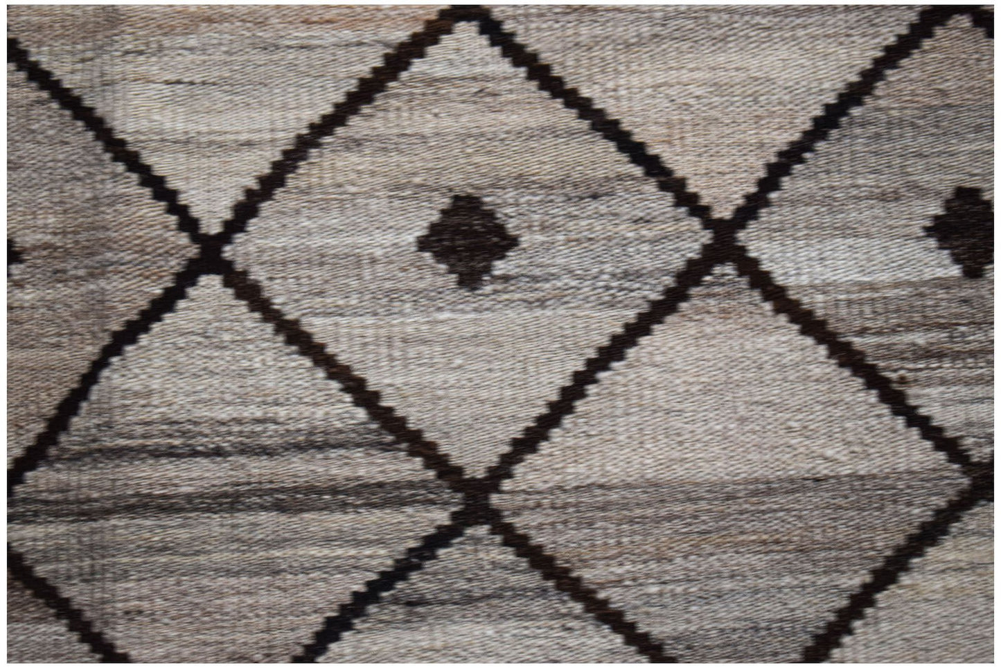 Handwoven Afghan Maimana kilim featuring a dark brown diamond pattern on a textured grey background.