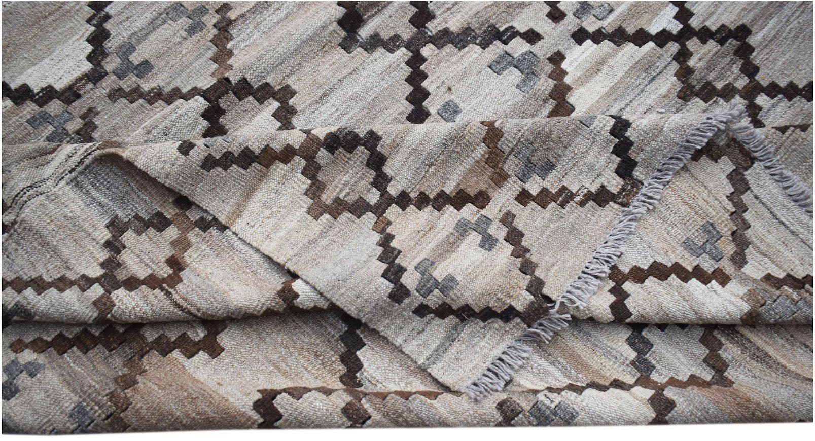 A handwoven Afghan Maimana kilim rug featuring a geometric pattern in neutral earth tones.