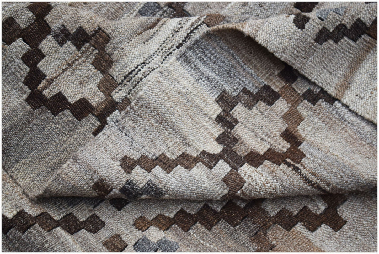 A handwoven Afghan Maimana kilim featuring a geometric pattern in shades of brown and beige.