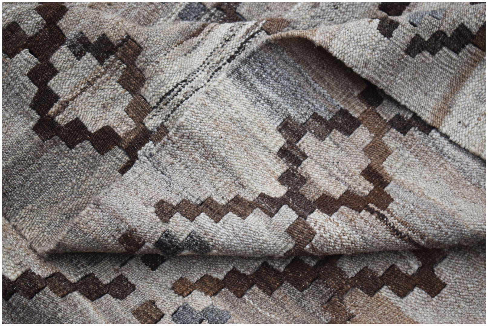 A handwoven Afghan Maimana kilim featuring a geometric pattern in shades of brown and beige.