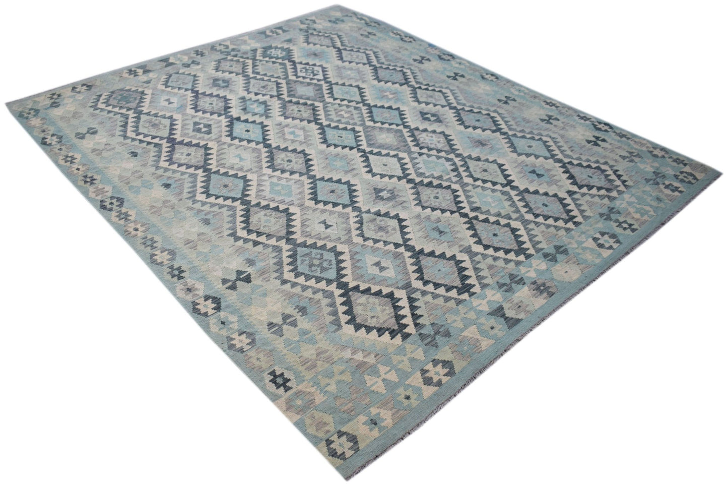 A handmade Afghan Maimana kilim rug featuring a geometric diamond pattern in shades of blue and grey.