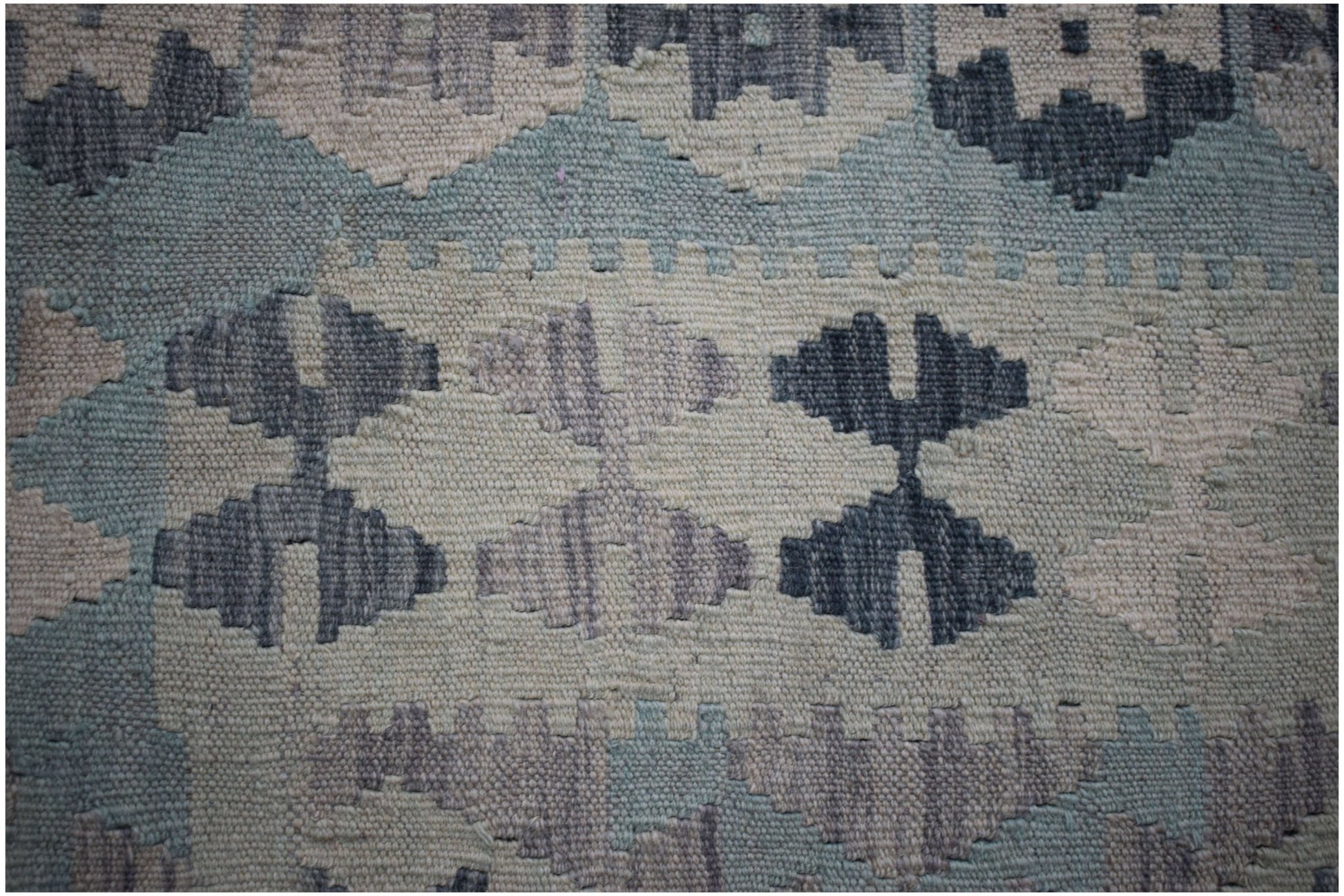 A close-up of a handmade Afghan Maimana kilim featuring a geometric pattern in blue and grey tones.