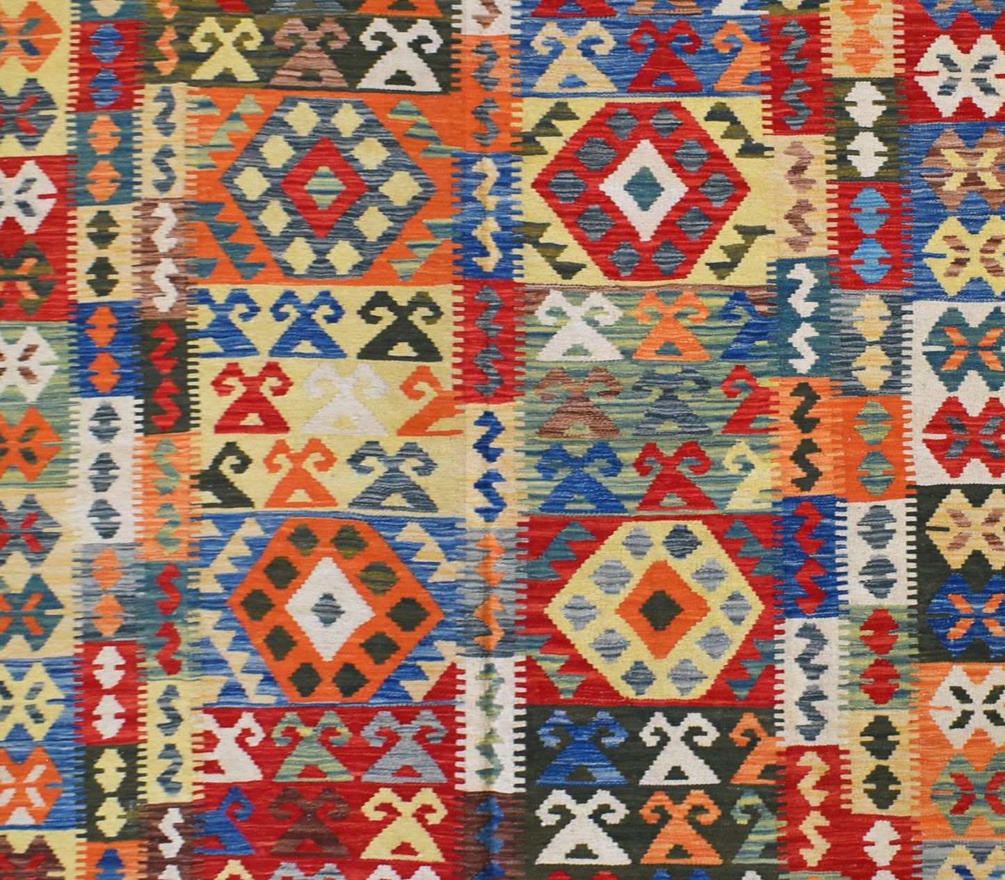 Handmade Afghan Maimana kilim rug featuring a vibrant geometric pattern in rich, multicolored wool.
