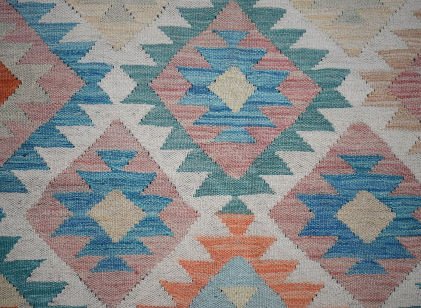 Handwoven Afghan Maimana kilim rug featuring a geometric diamond pattern in blue, pink, and orange.