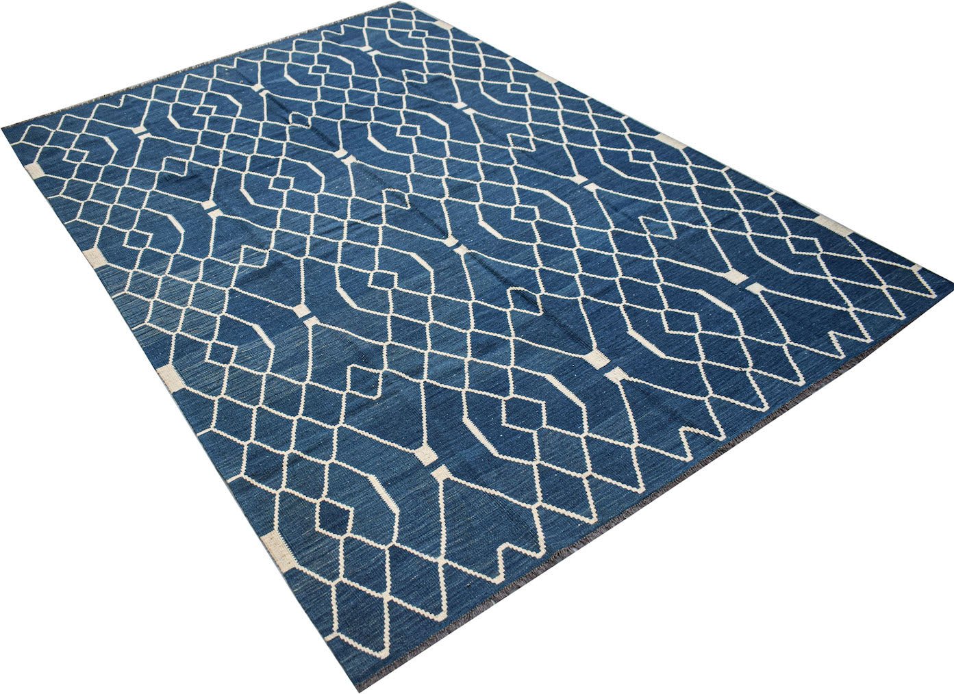 A handmade Afghan Maimana kilim rug featuring a geometric white pattern on a deep blue background.
