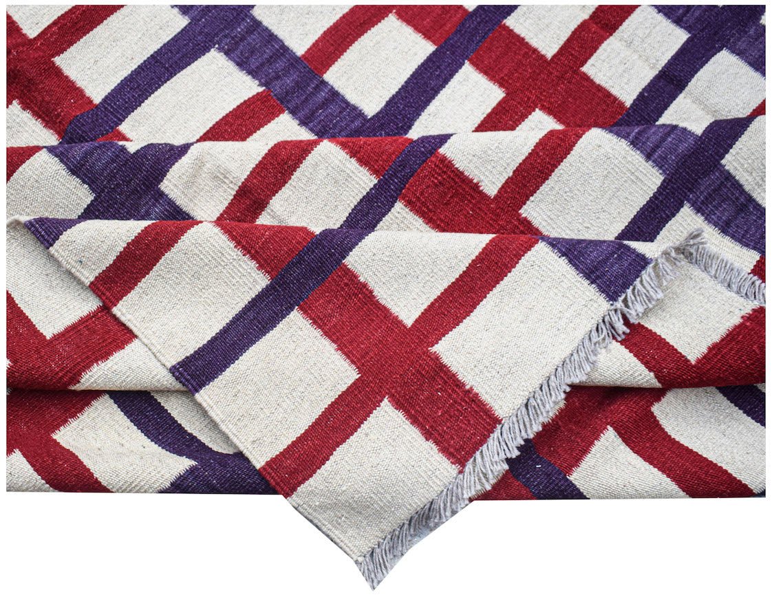 Handwoven Afghan Maimana kilim featuring a geometric grid pattern in red, purple, and cream wool.