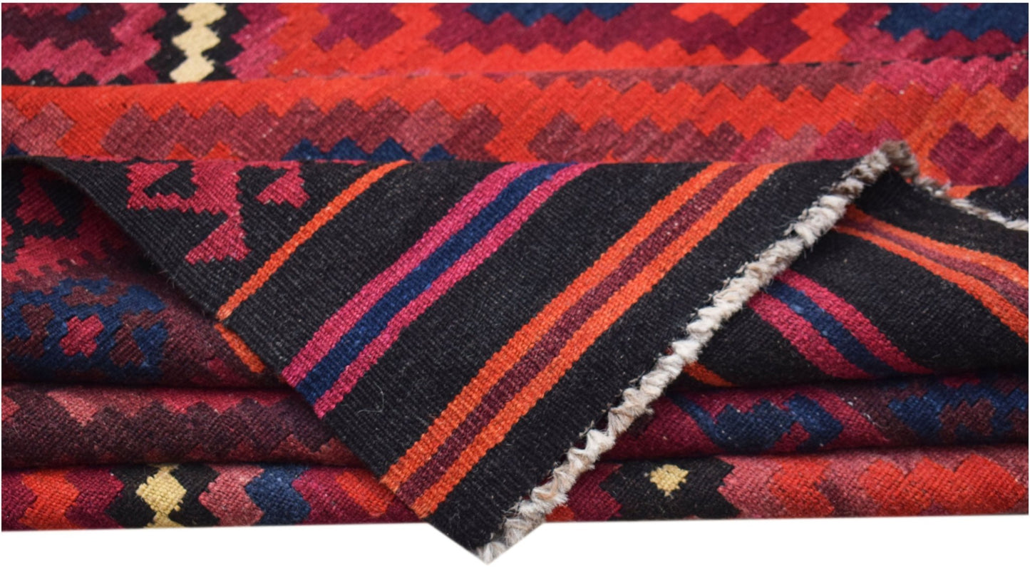 A folded Afghan Maimana kilim featuring geometric patterns in red, blue, and black wool.