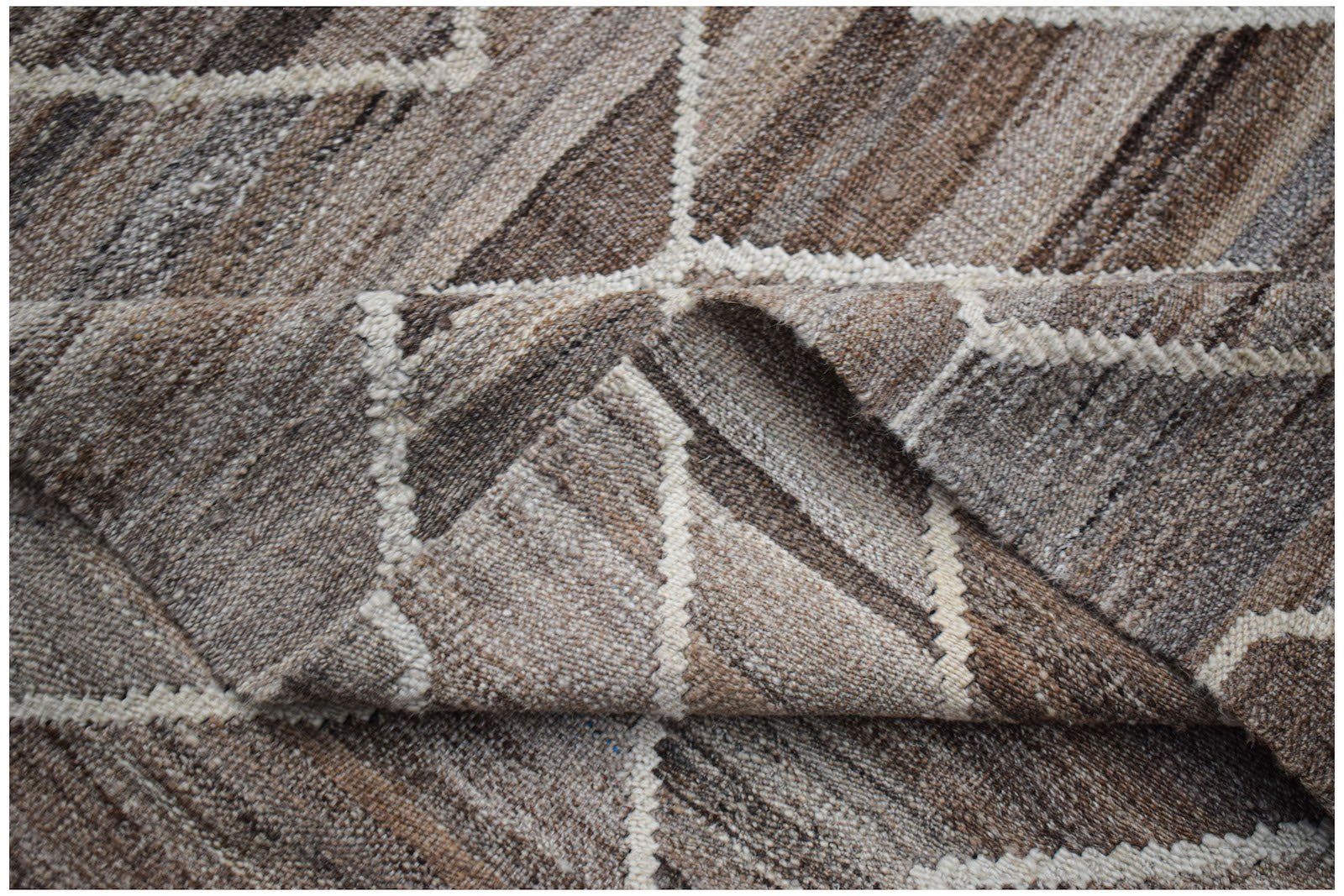 A handmade Afghan Maimana kilim rug featuring a geometric pattern in shades of brown and cream.
