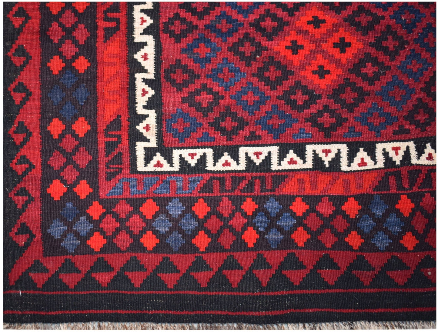 Handwoven Afghan Maimana kilim featuring a geometric pattern in red, blue, and black wool.
