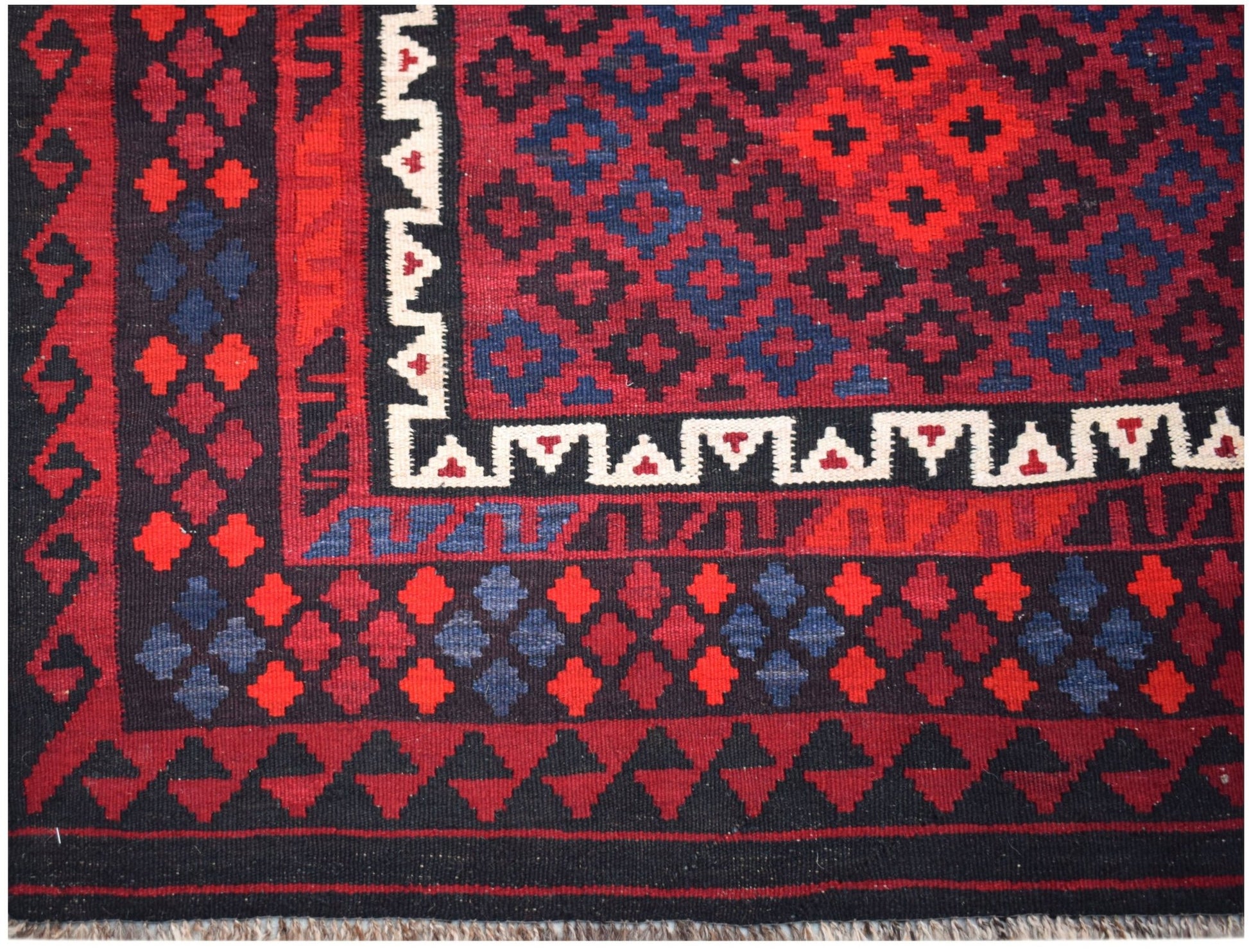 Handwoven Afghan Maimana kilim featuring a geometric pattern in red, blue, and black wool.