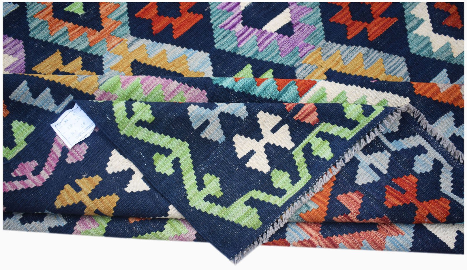 A handwoven Afghan Maimana kilim rug featuring a geometric pattern in vibrant multicolored wool.