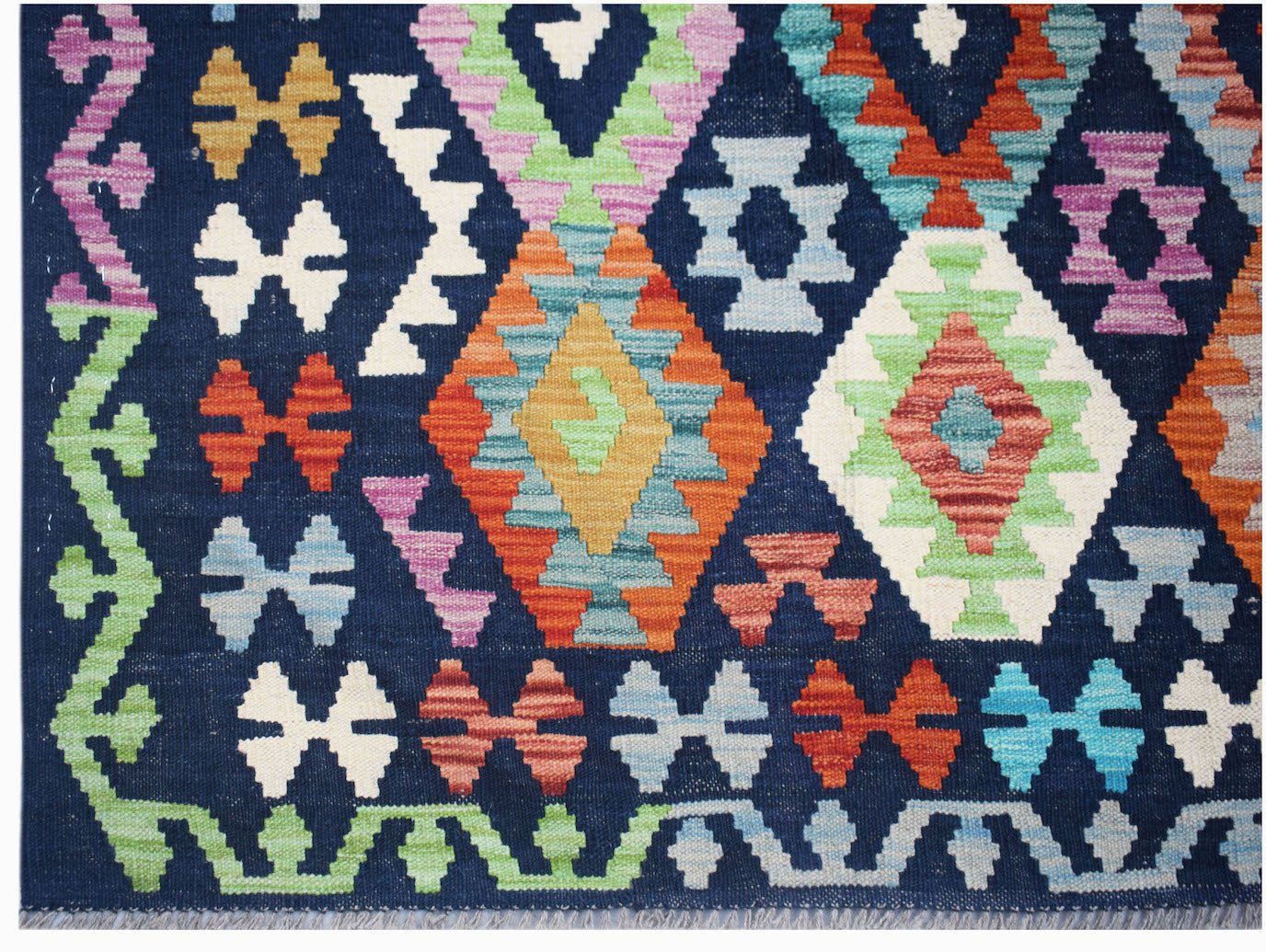 Handwoven Afghan Maimana kilim rug featuring a vibrant geometric pattern on a dark blue background.