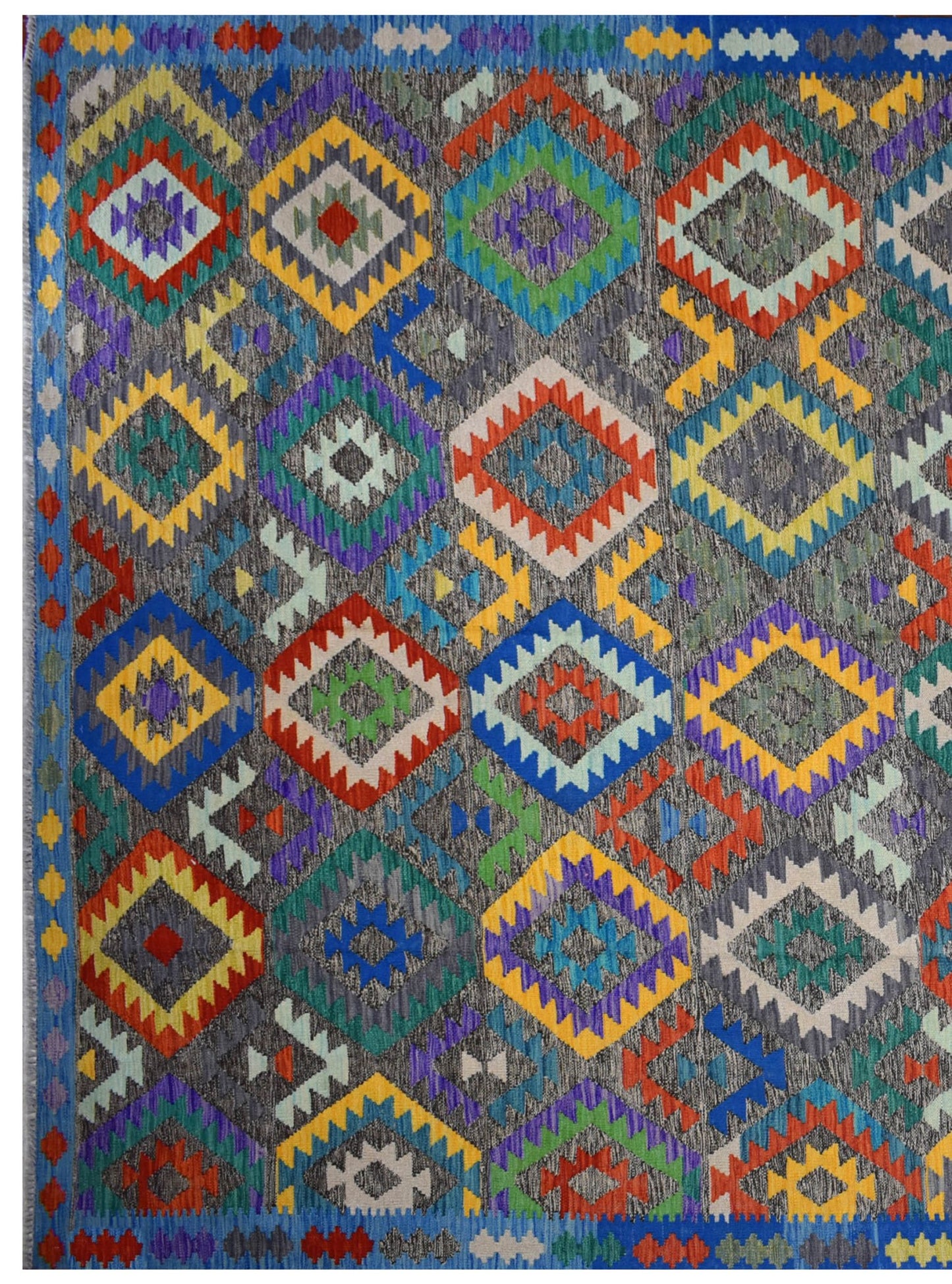 Handmade Afghan Maimana kilim rug featuring a vibrant geometric diamond pattern on a grey background.