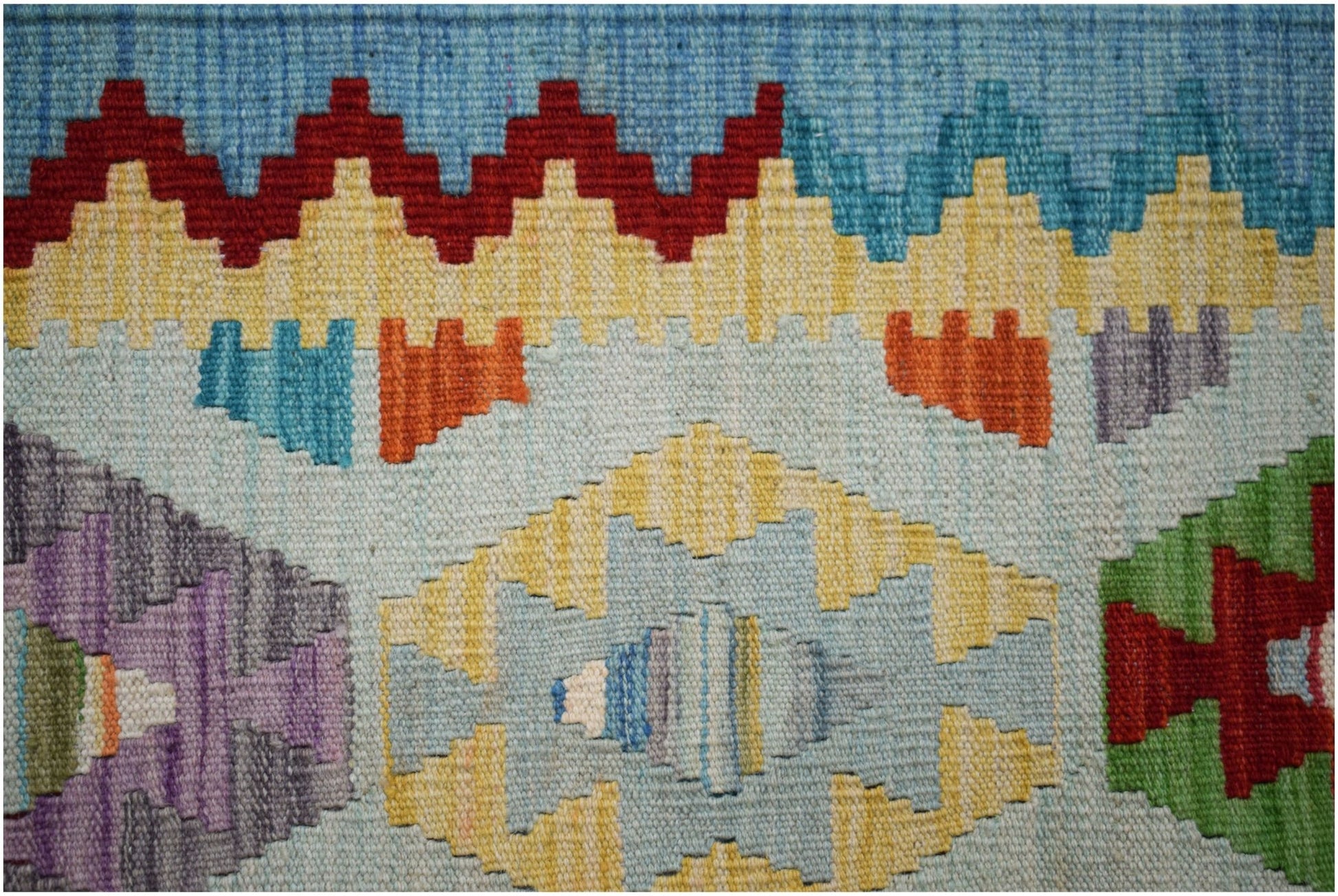 A handwoven Afghan Maimana kilim featuring geometric patterns in vibrant, multicolored wool.