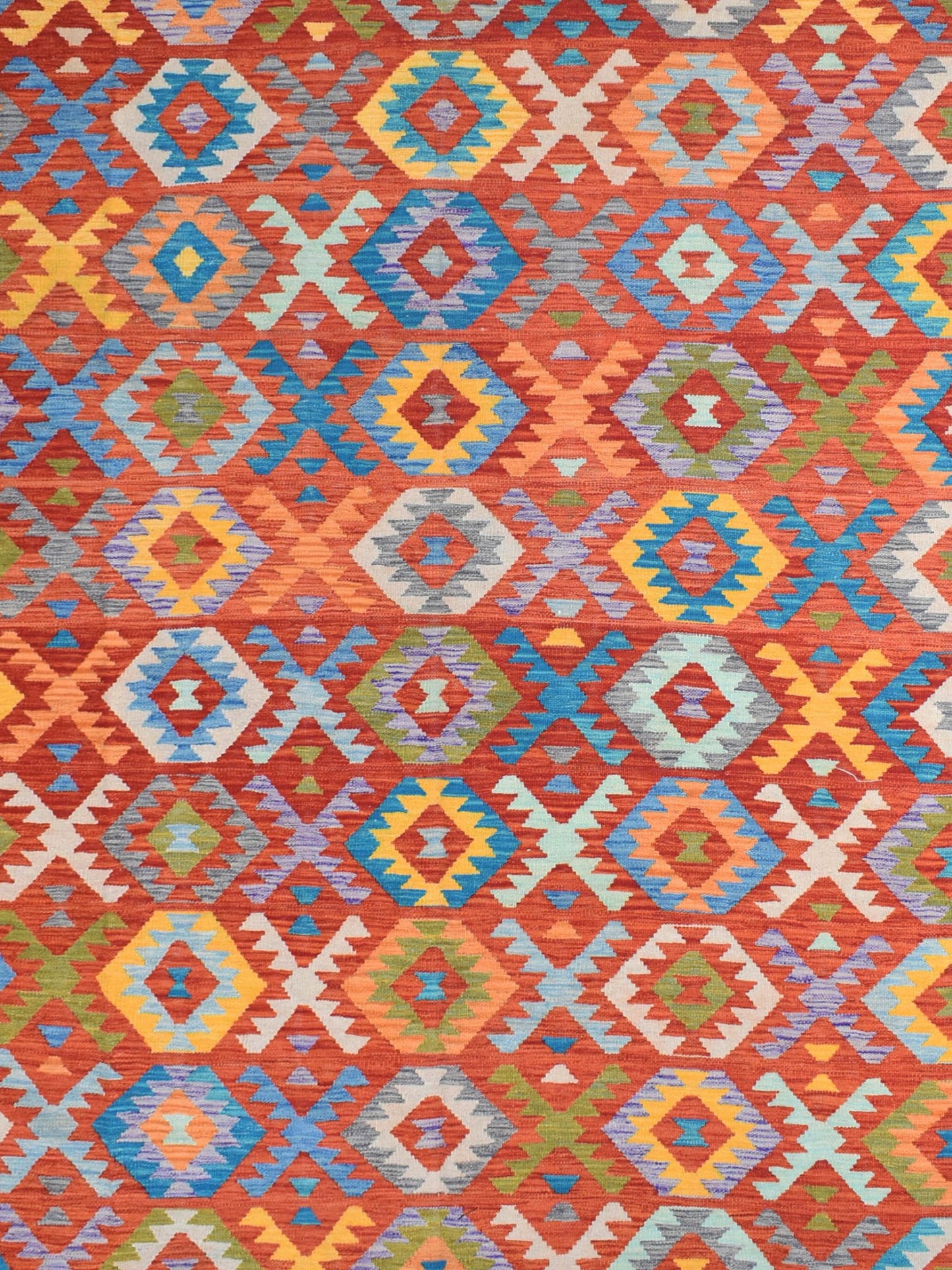Handmade Afghan Maimana kilim rug featuring a vibrant geometric pattern in warm, rich colors.