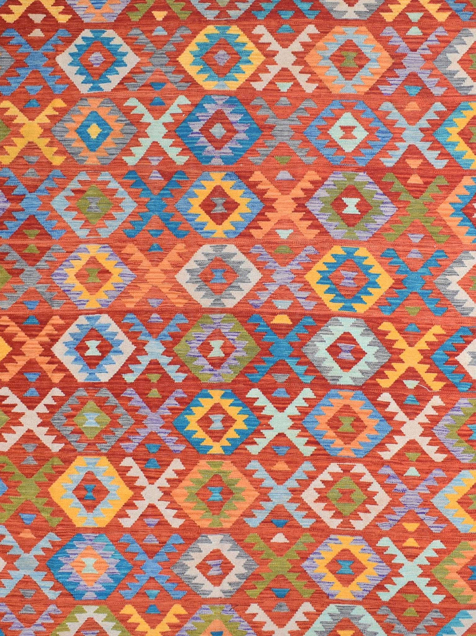 Handmade Afghan Maimana kilim rug featuring a vibrant geometric pattern in warm, rich colors.